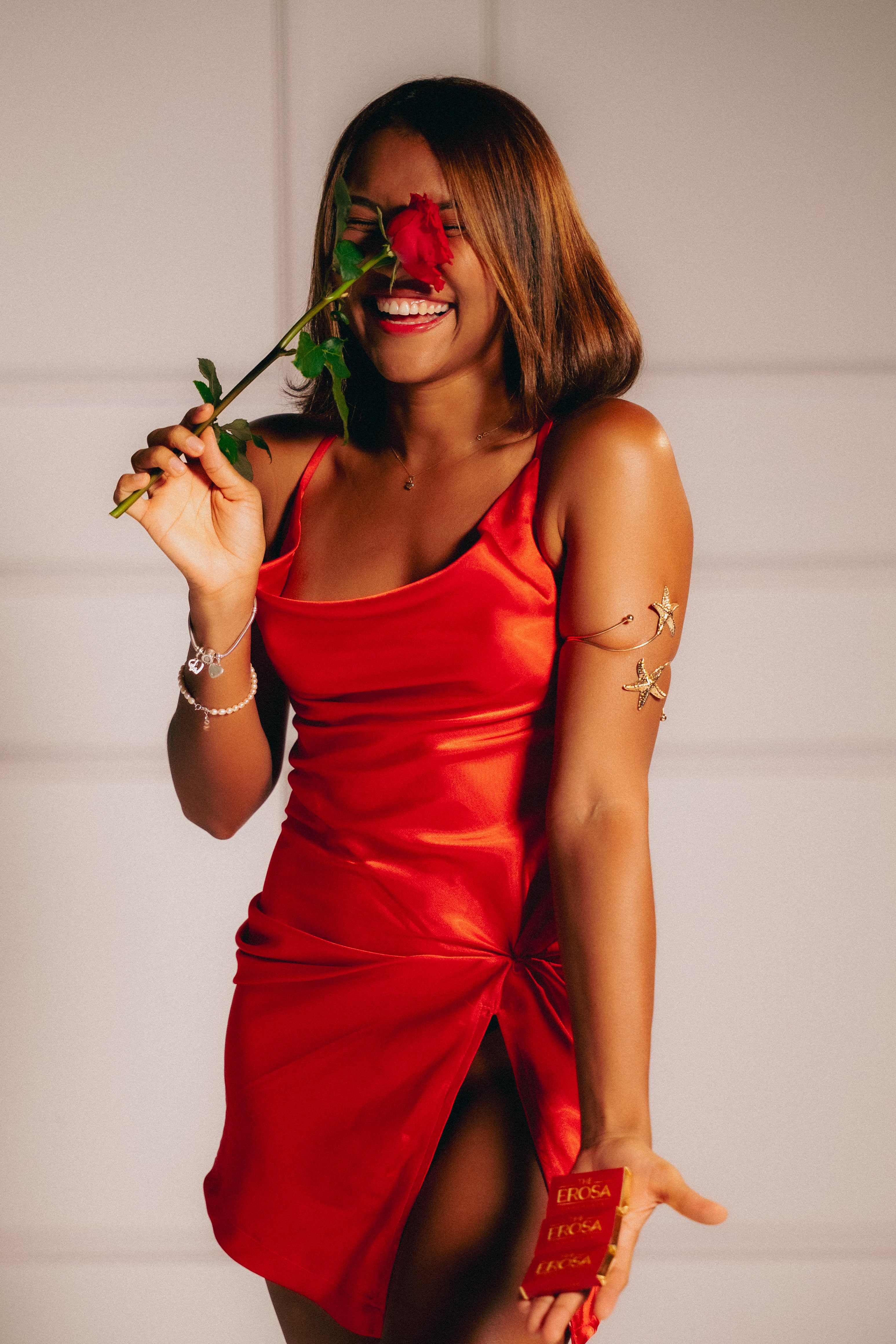 Woman in a red dress holding a rose and smilling
